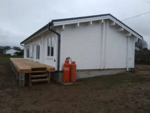 A mobile home granny annexe painted white with gas bottle beside it