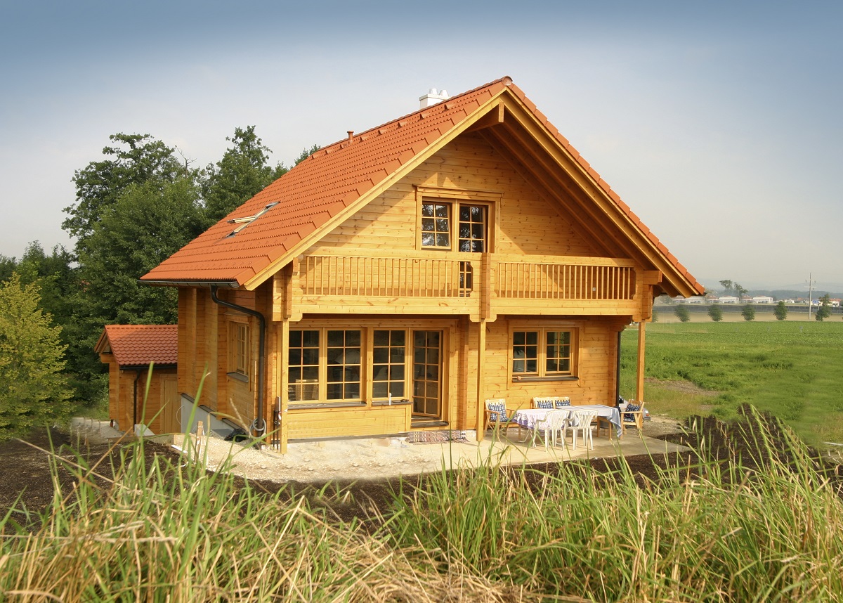 A photo of the Koiteli log home showing the balcony and terrace with a dining table and chairs on it.