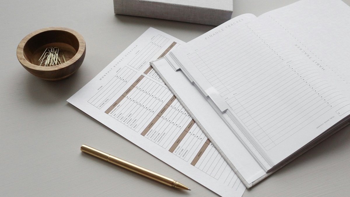 A photo of a journal on a desk with a bowl and paper clips
